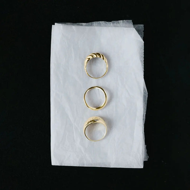 Solid 9ct yellow gold twisted rope ring shown alongside other gold rings