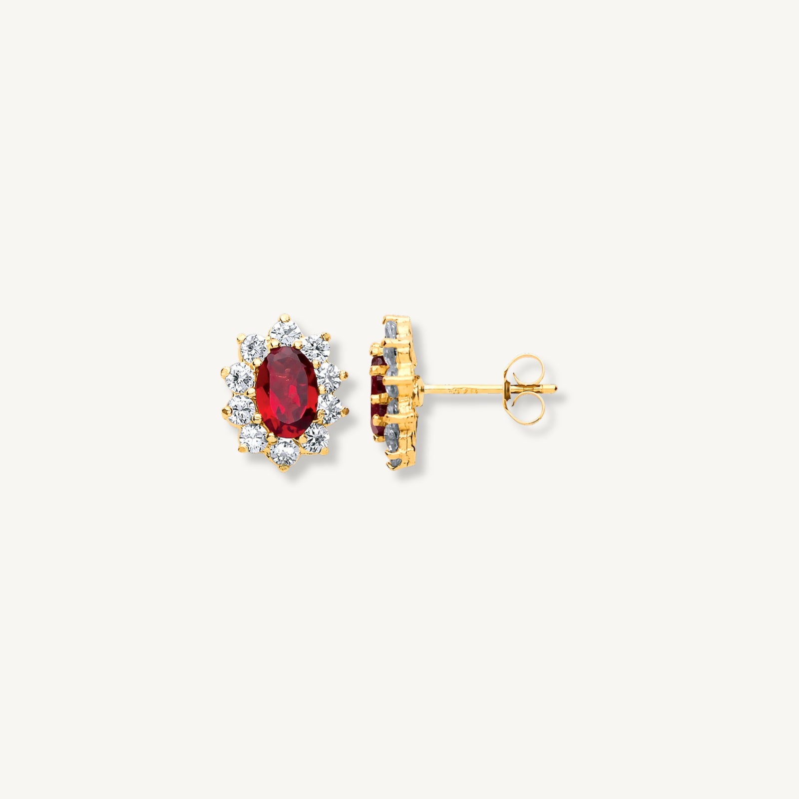 Gold earrings with a central red gemstone on a white background