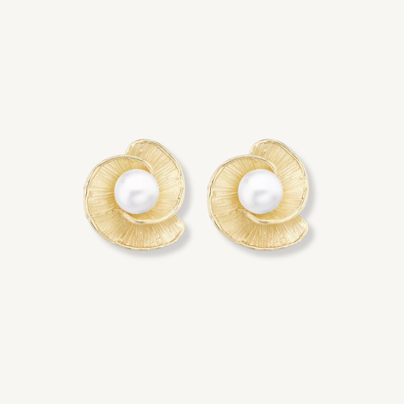 Gold earrings with pearl centers on a white background