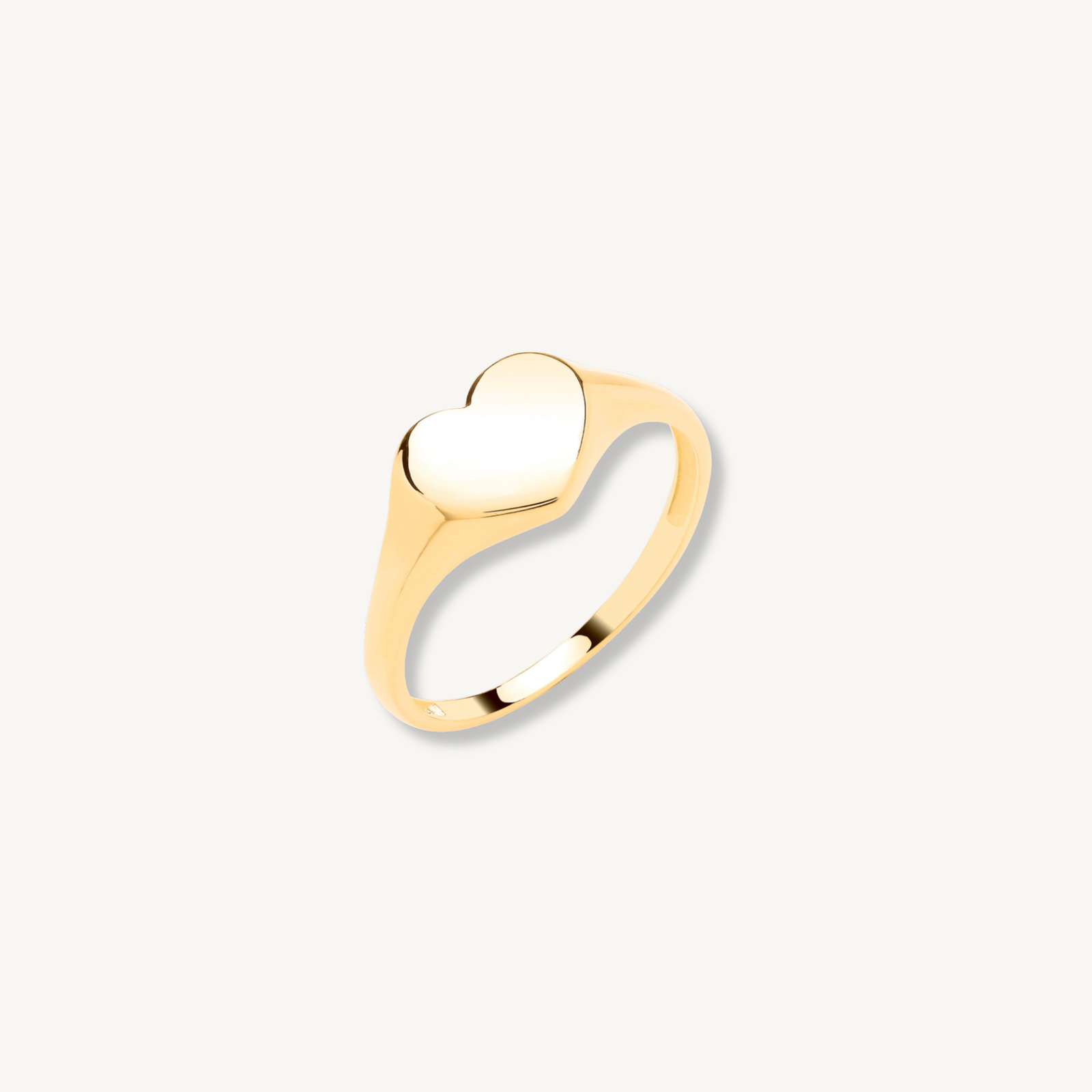Gold ring with a heart-shaped center on a light gray background