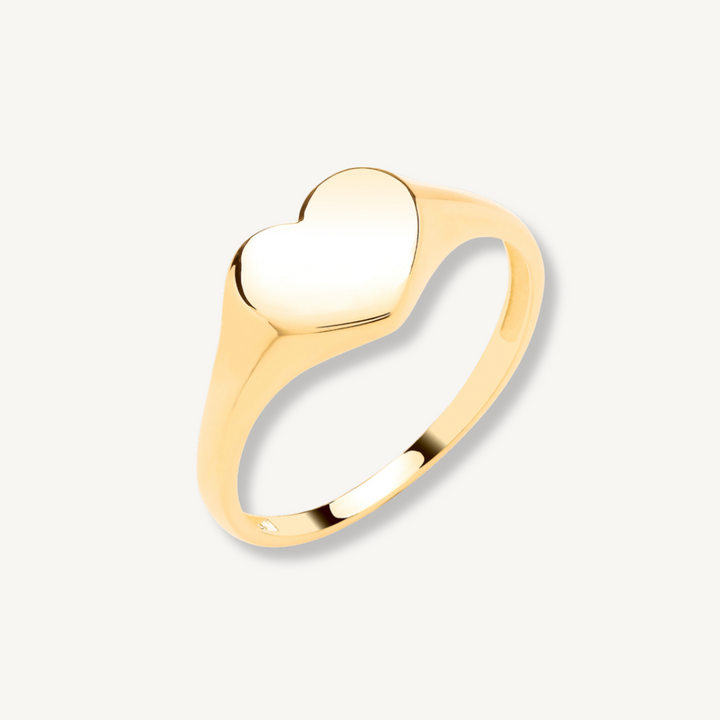 Gold ring with a heart-shaped center on a light gray background